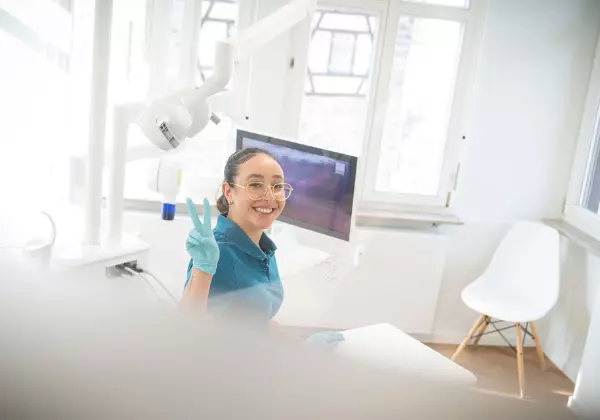 Mitarbeiterin der Zahnarztpraxis Confident lächelt nach erfolgreicher Parodontitis Behandlung 